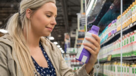 young woman reads nutrition label on dairy product in supermarket